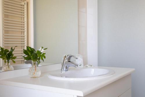 a white bathroom with a sink and a mirror at Le clos aux roses in Chédigny