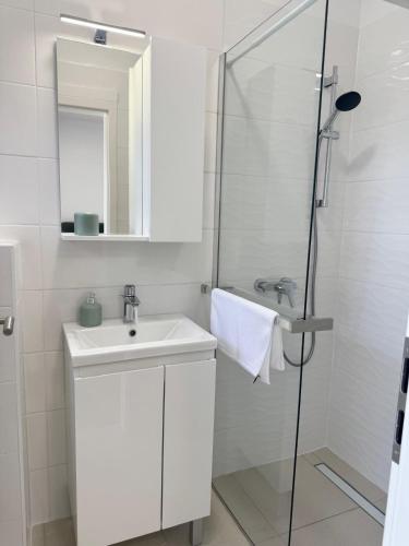 a white bathroom with a sink and a shower at Studio Sanja in Vlašići
