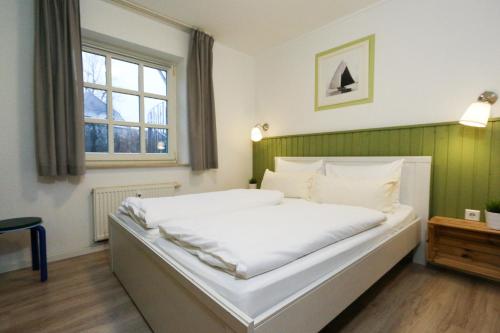 a bedroom with a large white bed and a window at Captain Pahlen Ferienanlage in Zingst