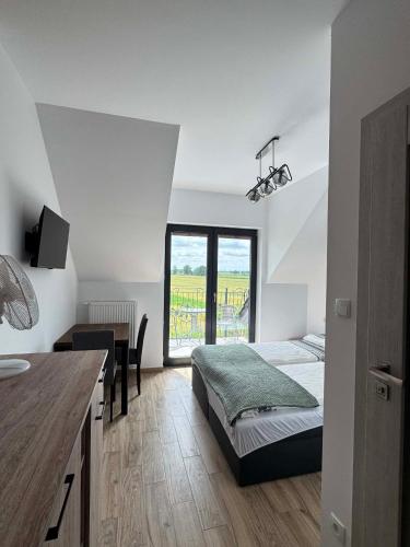 a bedroom with a bed and a desk and a window at Rajska Zatoka Jantar in Jantar