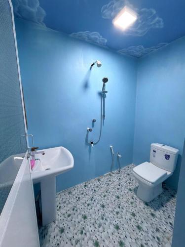 a blue bathroom with a toilet and a sink at Afaa Beach Guest House in Arugam Bay