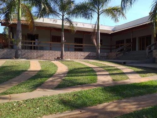 a building with palm trees in front of a sidewalk at chacara Recanto do ssosego in Olímpia