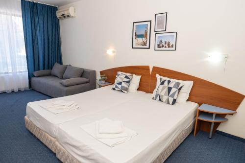 a hotel room with a large bed and a chair at Hotel M2 in Primorsko