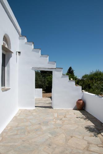 a white house with a stone floor and stairs at Visinokipos House in Mirsíni