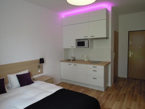 1 dormitorio con 1 cama y cocina con luz morada en Apartamenty Karawela - Nadmorski Dwór, en Gdansk