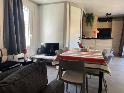 a living room with a table and a couch at CHALET 10 chaleureux tout confort dans domaine avec Piscine au cœur des Landes bord de Lac avec plage aménagée in Labouheyre