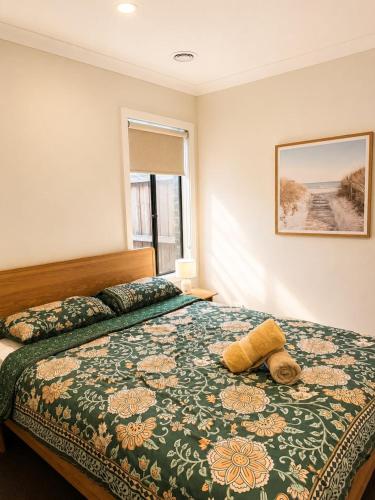 a bedroom with a bed with a green comforter at Modern Family Home in Truganina - Space to Relax in Truganina
