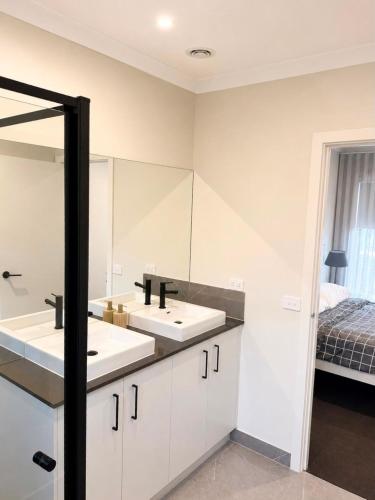 a bathroom with two sinks and a mirror at Modern Family Home in Truganina - Space to Relax in Truganina