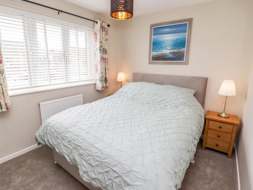 a bedroom with a white bed and a window at 7 Cwrt Y Cadno in Llantwit Major