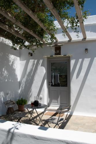 a table and chairs on the side of a white wall at Visinokipos House in Mirsíni