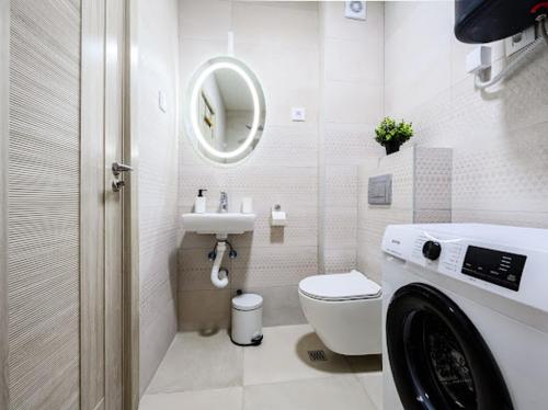 a white bathroom with a toilet and a sink at Apartman Adriatico 10 in Šušanj