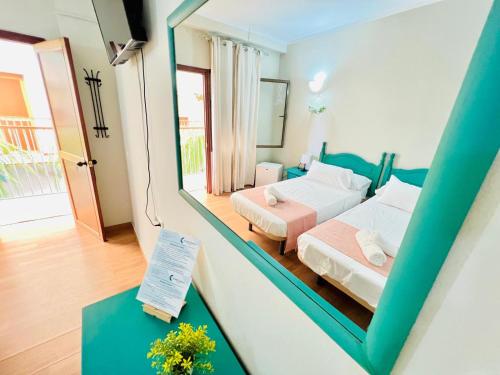 a room with two beds and a mirror at Hostal Cristina in Chipiona