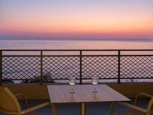 two wine glasses on a table on a balcony with the ocean at Nana Golden Beach All Inclusive Resort & Spa in Hersonissos