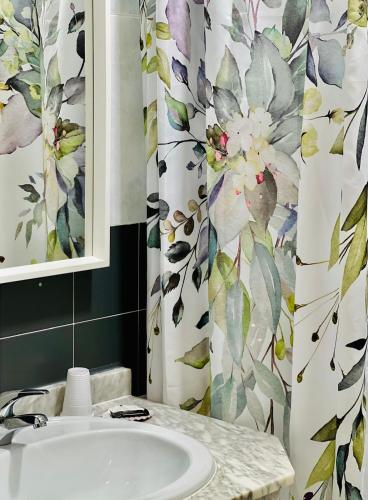 a bathroom with a sink and a shower curtain at Hostal Cristina in Chipiona