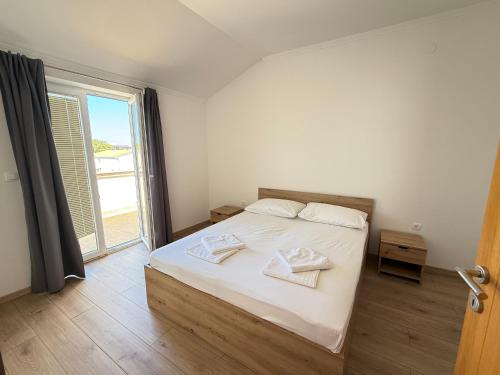 a bedroom with a bed with white sheets and a window at Apartments Palma Novalja in Novalja