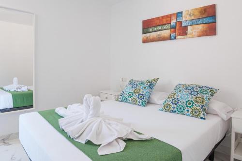 a white bedroom with a white bed with a green blanket at Rayito de sol 3 in Costa de Antigua