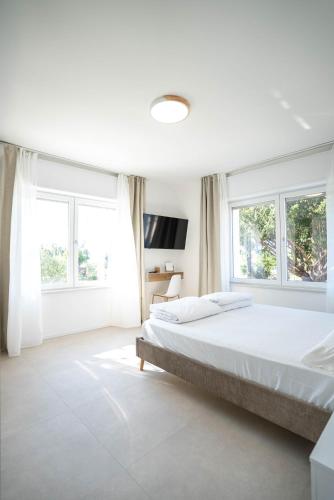 a white bedroom with a large bed and windows at Corte Fossalta - Casa Linda in Lazise