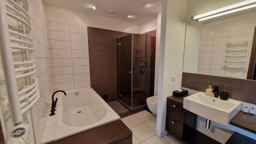 a bathroom with a tub and a sink and a shower at Modern skyline-view condo at a luxury complex in Vilnius