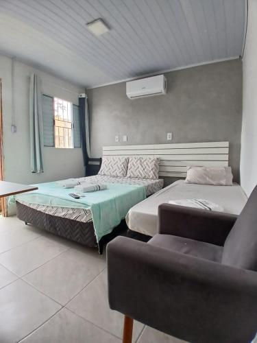 a bedroom with two beds and a couch at Hotel New in Alegrete