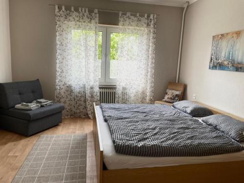 a bedroom with a bed and a chair and a window at Am Weserradweg in Porta Westfalica