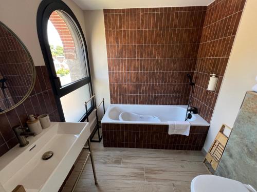 a bathroom with a tub and a sink at Suite Rivière in Lèves