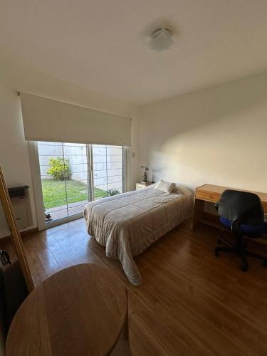 a bedroom with a bed and a desk and a window at Descanso Sereno in Junín