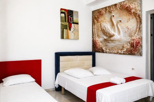 two beds in a room with a painting on the wall at Hotel Erisun in Vlorë