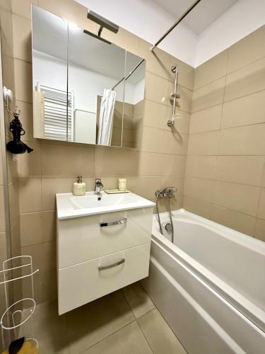 a bathroom with a sink and a tub and a mirror at Contemporary Studio with Balcony - New Building in Bucharest
