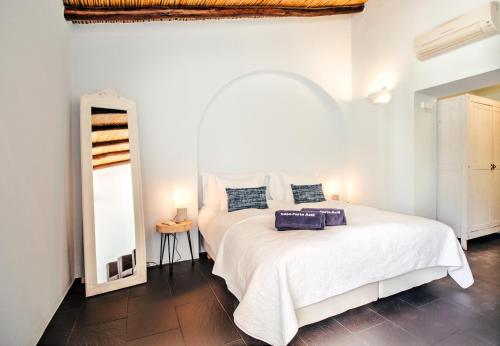 a white bedroom with a white bed and a mirror at Casa Porta Azul in Boliqueime