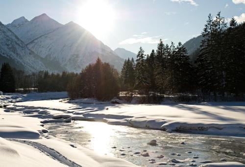 a river covered in snow with mountains in the background at Ferienwohnungen Schlichtherle in Bach