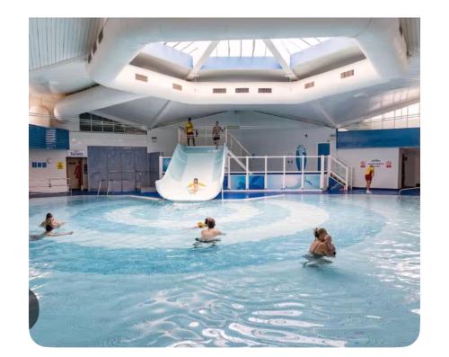 a group of people swimming in a swimming pool at Explorer45 in Lytchett Minster