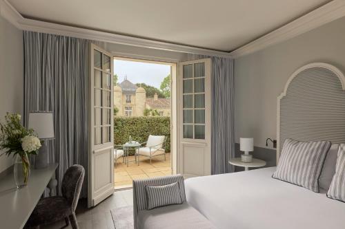 a bedroom with a bed and a balcony with a table at COMO Cordeillan-Bages in Pauillac