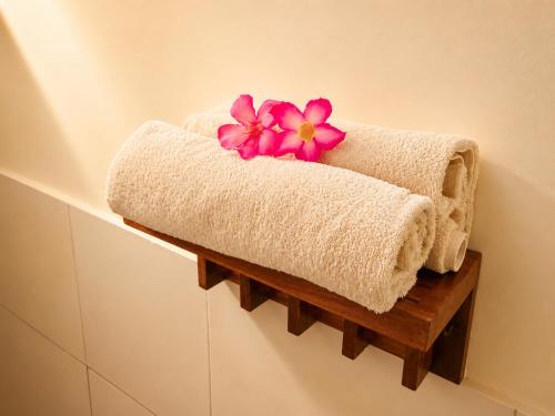 a towel holder with a pink flower on top of it at Lombok eco Bungalow in Gili Gede