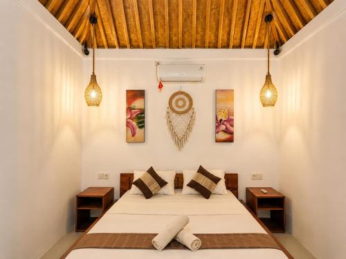 a bedroom with a bed and paintings on the wall at Lombok eco Bungalow in Gili Gede