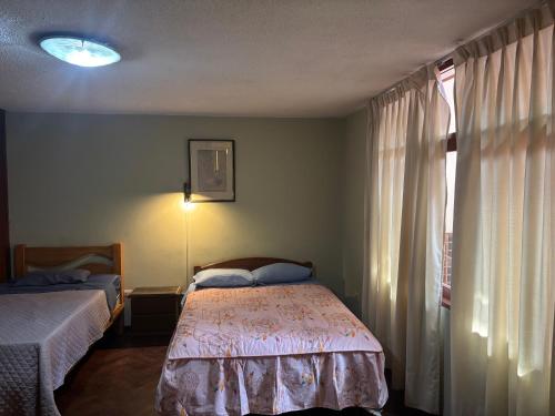 a bedroom with two beds and a window with curtains at Casa Junto al Rio in Arequipa