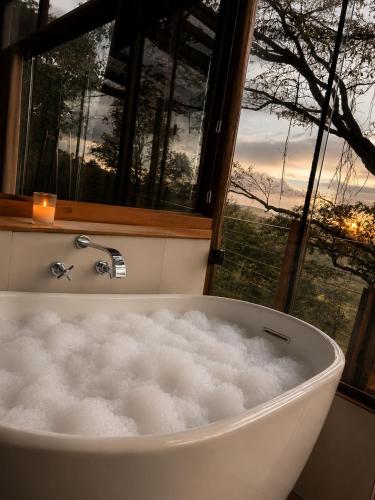 a bath tub in a room with a window at Chalé da Árvore - Refúgio das Videiras in Moeda