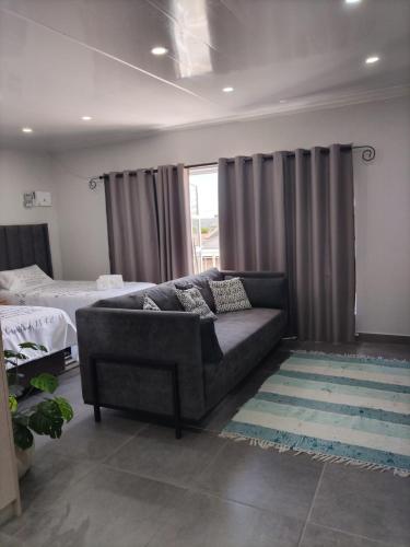 a living room with a couch and a bed at The Room Above in Brackenfell