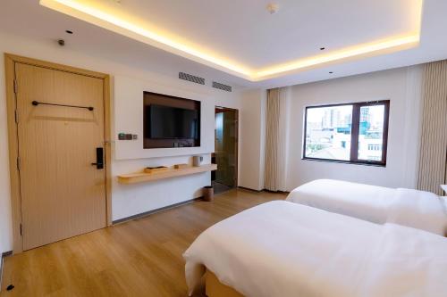 a bedroom with two beds and a flat screen tv at Hera Hotel in Hanoi