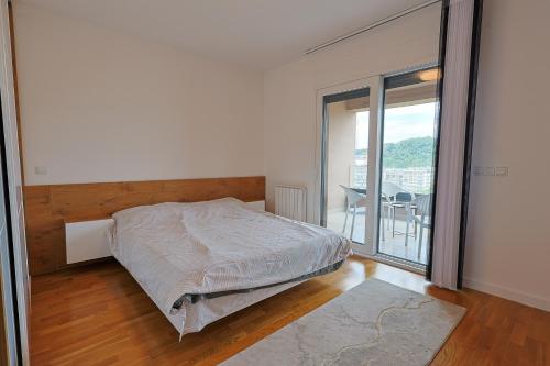 a white bedroom with a bed and a balcony at Tuzla Tower in Ši Selo