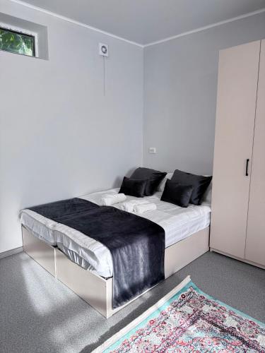 a white bedroom with a large bed with black pillows at Gatto in Bishkek