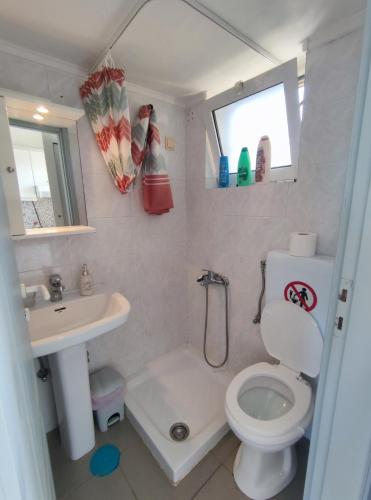 a small bathroom with a toilet and a sink at Seaview Studio in Gázion