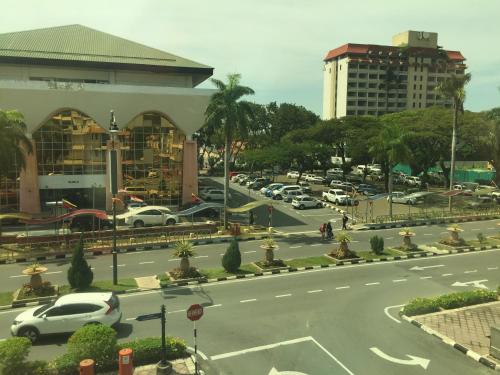 een stadsstraat met auto's geparkeerd op een parkeerplaats bij Premierz Hotel in Labuan