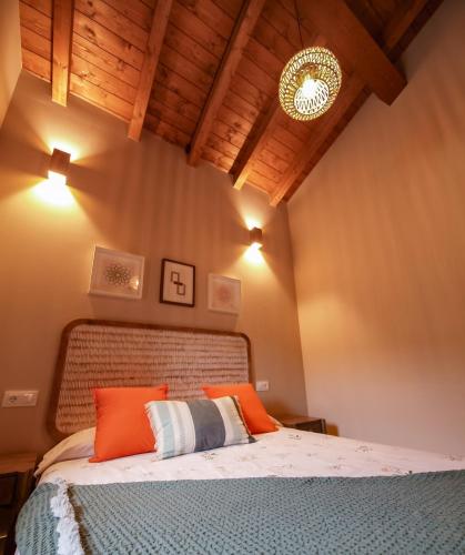 a bedroom with a bed with orange and white pillows at APARTAMENTOS PUENTEDEY in Puentedey