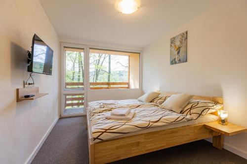 a bedroom with a bed and a tv on a wall at Penzion Kopaninky in Bítov