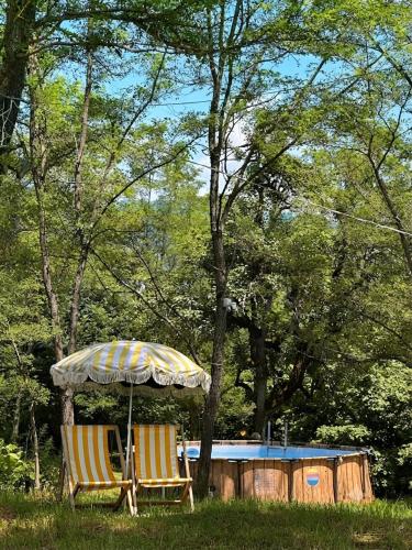 two chairs under an umbrella next to a house at Jvarisa Glamping in Ambrolauri