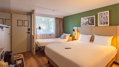 a hotel room with two beds and a window at Campanile NATURE - Biarritz in Biarritz