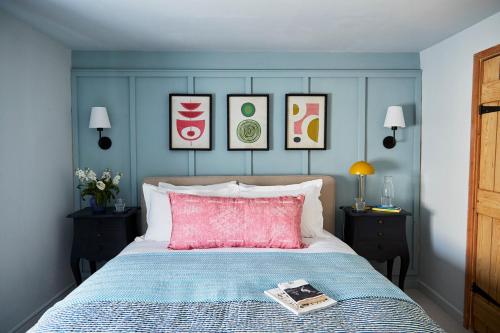 a bed with a pink pillow and a book on it at NEW Stylish Cosy Dog Friendly Cottage Parking Central in Oundle