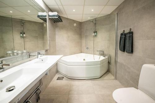 a bathroom with a tub and a toilet and a sink at Hotel Stensson in Eslöv