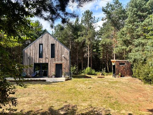 a wooden house in the middle of a yard at Forest Cabin Modern Barn and Private Woods in Jamielnik