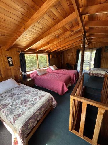 a bedroom with two beds in a wooden cabin at Cabañas Puchuman Lican Ray in Licán Ray